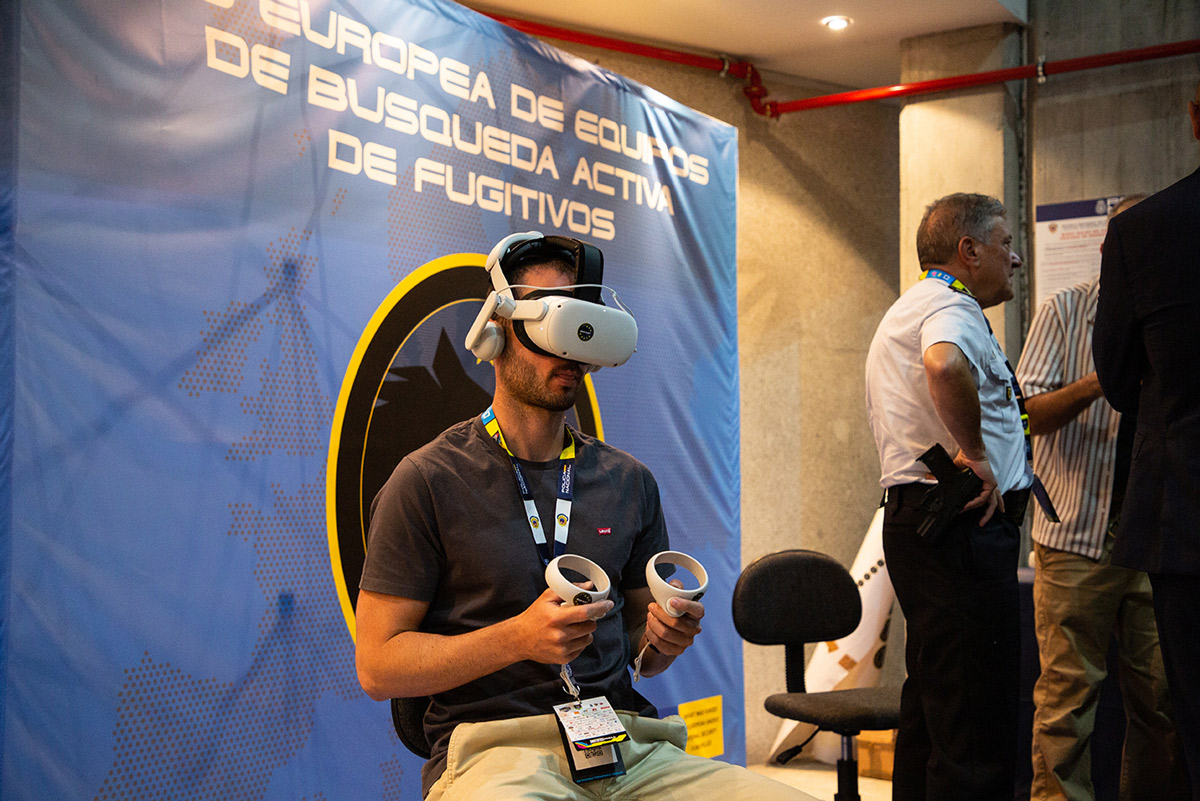 Foto de un asistente al Congreso C1b3rWall probando unas gafas y mando de realidad virtual.