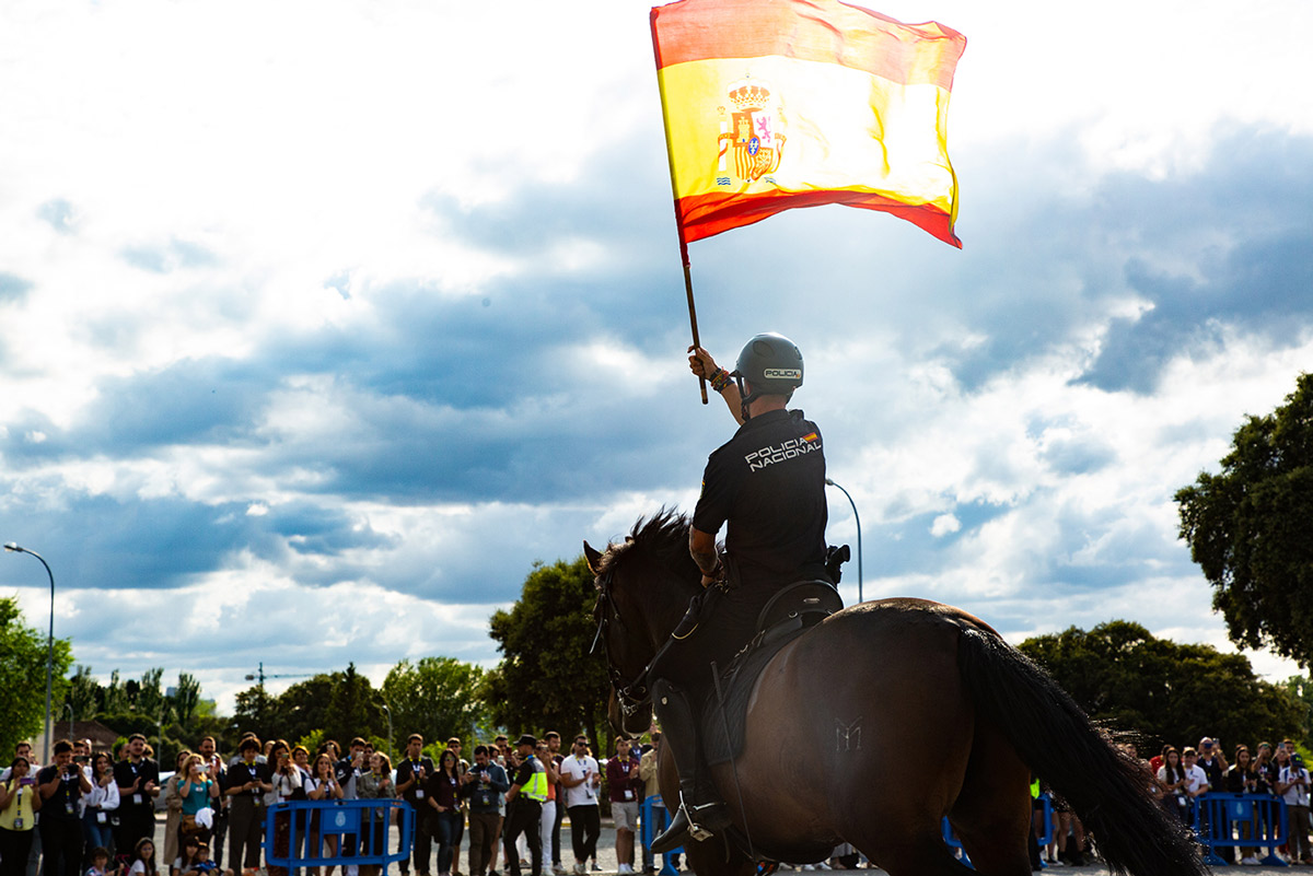 Foto de un Policía de la Unidad Especial de Caballería montado sobre su caballo y llevando la bandera de España.