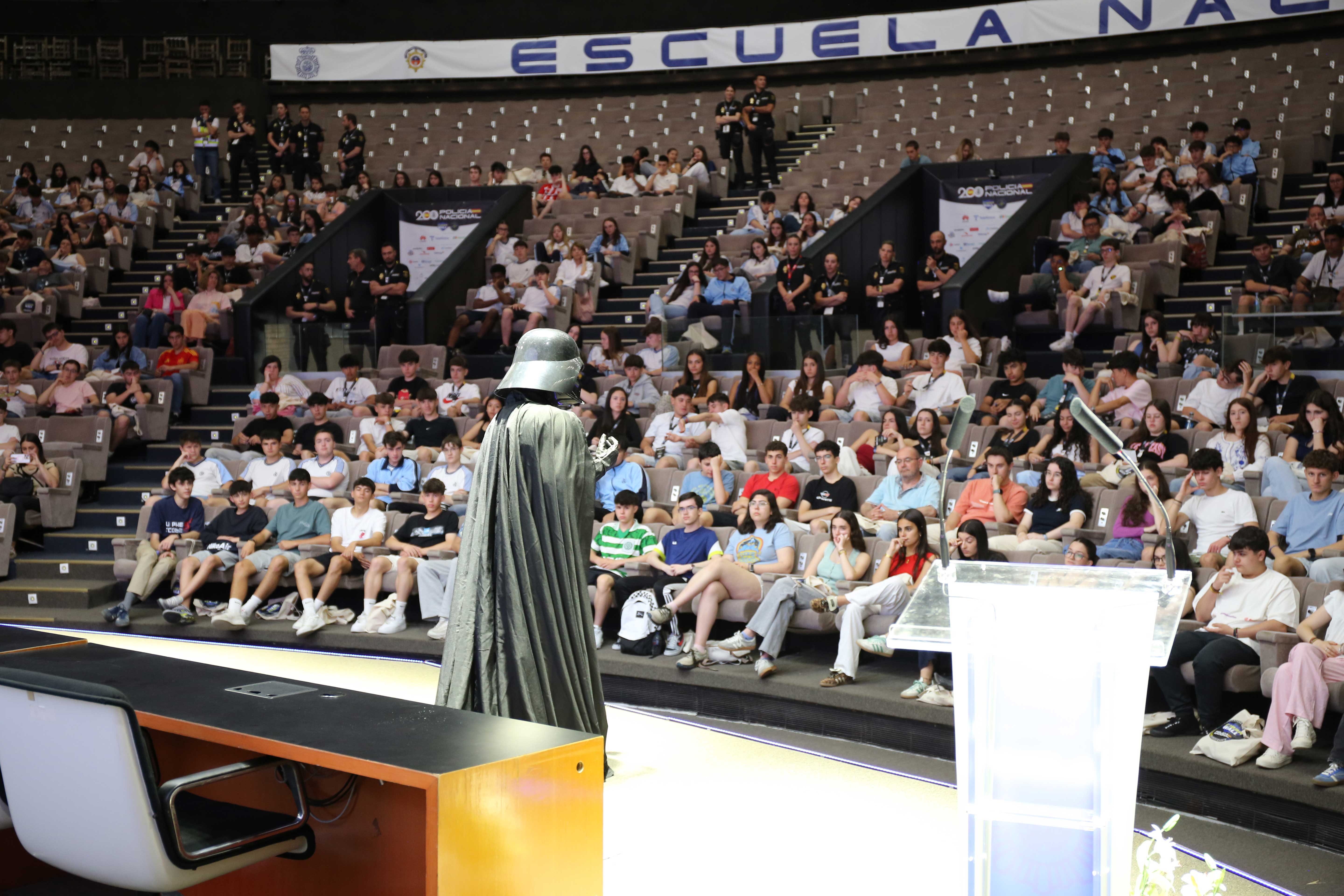 Fotografía de una persona disfrazado de Darth Vader dando una conferencia a jóvenes en el congreso C1b3rWall 2025